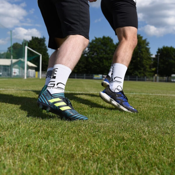 Skarpety antypoślizgowe na boisku piłkarskim w korkach i butach do biegania